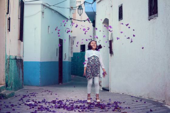 Young girl laughing as petals fall around her